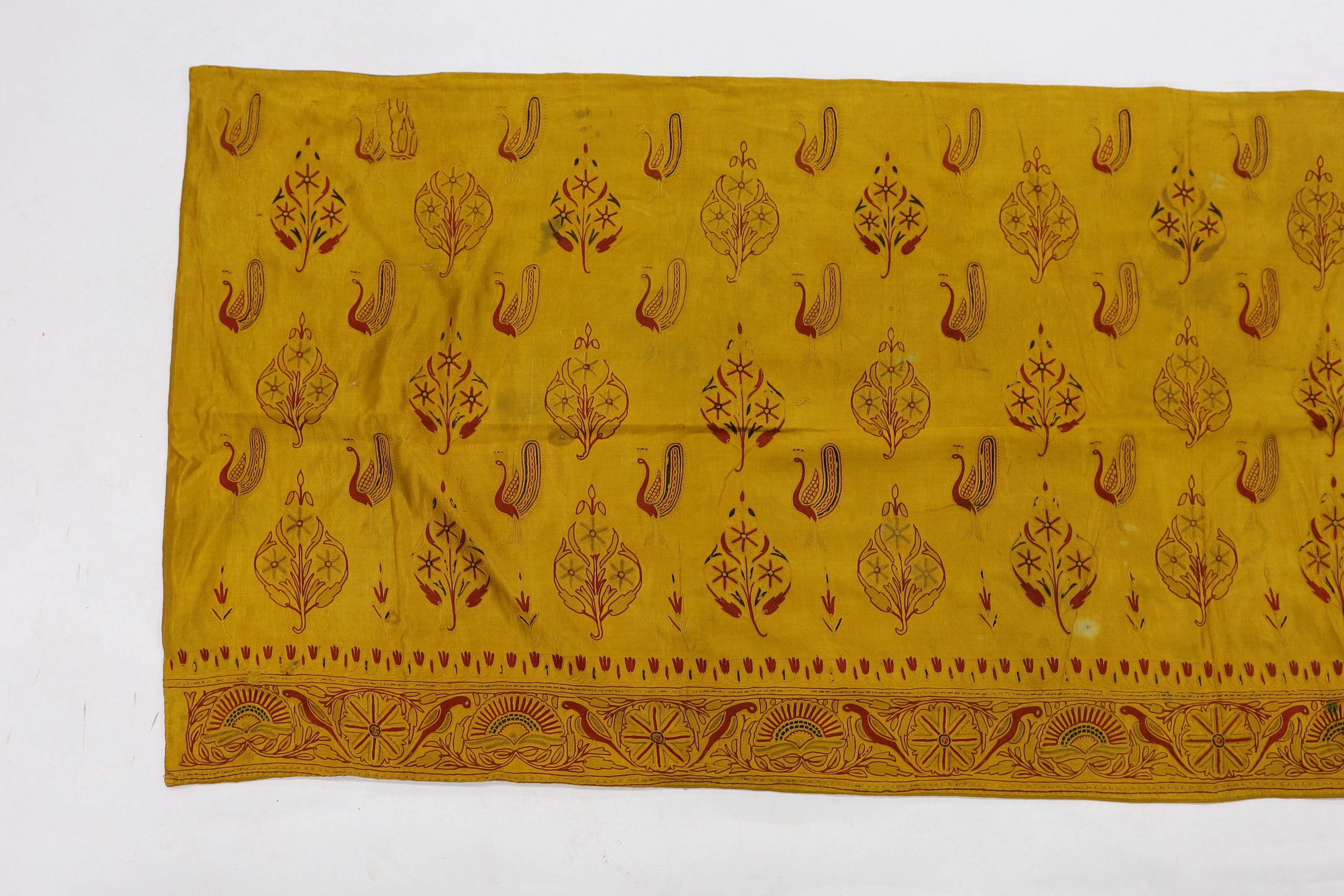 A 19th century fine cream woven Kashmiri shawl with blue and red teardrop design borders, an early 20th century gold satin pelmet with spot motifs of peacocks and flowers, 204cm long x 71cm high and a length of silk with